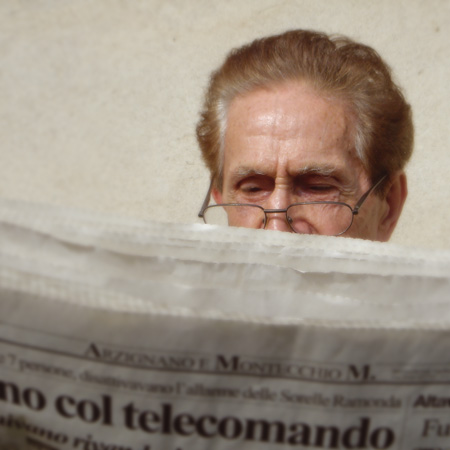 Persona anziana legge un quotidiano.